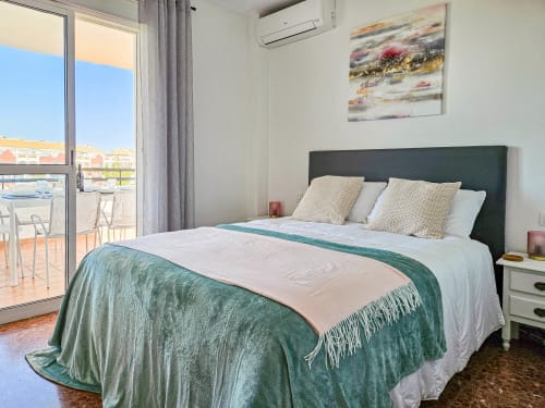 Moderno dormitorio en apartamento SACORO de Marbella con cama queen, acceso a terraza y vistas al jardín