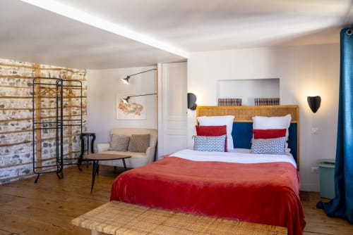 Chambre Sancy à La Tour Grégoire à Clermont-Ferrand : lit en velours rouge, tête de lit tissée et mur de briques moderne