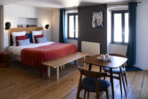 Chambre Sancy à La Tour Grégoire à Clermont-Ferrand : chambre moderne avec literie rouge, mobilier en bois et accès au balcon