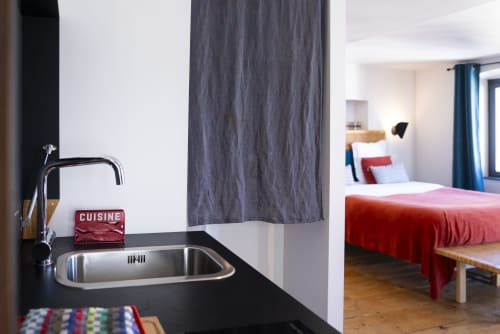 Kitchenette moderne avec évier en acier inoxydable et chambre à literie rouge à La Tour Grégoire, Clermont-Ferrand