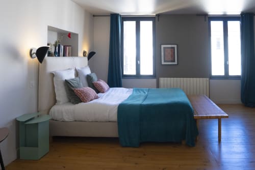 Chambre moderne à La Tour Grégoire Clermont-Ferrand avec literie vert-bleu, oreillers blancs, parquet et vue sur la ville