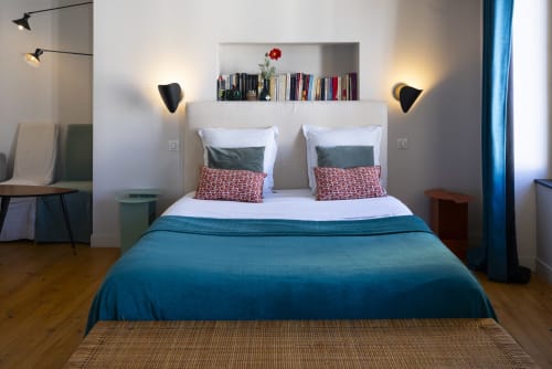Chambre moderne à la Tour Grégoire à Clermont-Ferrand avec literie bleu-vert, rangements muraux et éclairage élégant.