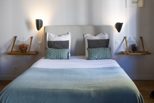 Chambre moderne à La Tour Grégoire à Clermont-Ferrand avec lit queen-size, literie bleu canard et appliques murales contemporaines