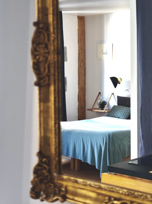 Chambre de la Maison d'hôtes La Tour Grégoire à Clermont-Ferrand avec literie bleue, poutres apparentes et lampe suspendue