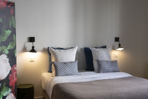 Chambre moderne à La Tour Grégoire à Clermont-Ferrand avec vue sur la ville, literie blanche, coussins à motifs et applique murale
