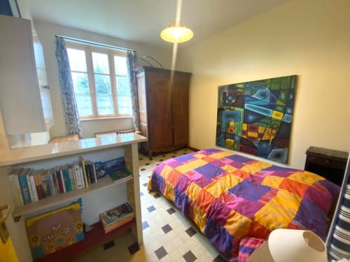 Bright bedroom with colorful patchwork quilt at Le Lama Zébré cottage, Penmarch, featuring bookshelves and garden view