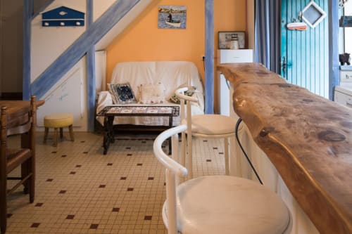 Fisher Sheep Cottage living area with wooden counter, cream chairs, and orange accent wall at Le Lama Zébré in Penmarch