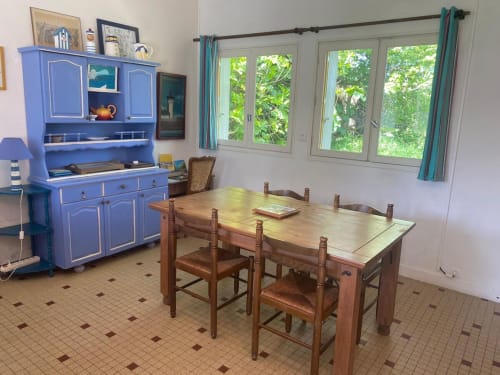 Fisher Sheep Cottage dining room at Le Lama Zébré with wooden table, chairs, blue buffet cabinet, and garden views through