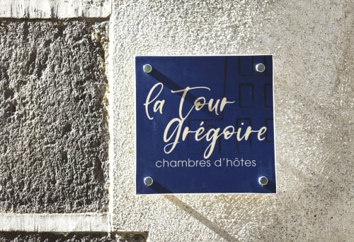 Enseigne de chambres d'hôtes La Tour Grégoire sur un mur de pierre à Clermont-Ferrand