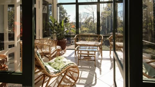 Véranda de l'Appartement 2 Personnes - salon en rotin ensoleillé avec plante tropicale et vue panoramique sur le jardin