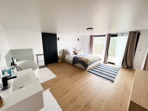 Chambre spacieuse de l'hôtel Anne Duval à Saint-Florent avec lit, salle de bains privée, parquet et accès à la terrasse