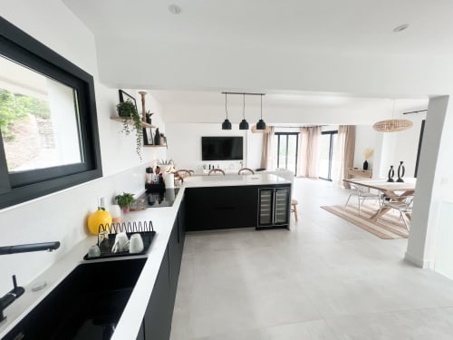 Cuisine ouverte moderne et salon de l'hôtel Anne Duval à Saint-Florent avec mobilier noir, plans de travail blancs