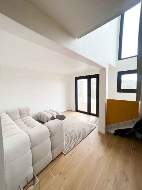 Salon contemporain de l'hôtel Anne Duval à Saint-Florent avec sièges blancs moelleux, parquet et portes vitrées sur terrasse