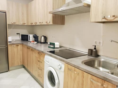 Cocina moderna del apartamento Top Home Integra en Jerez de la Frontera con gabinetes de madera, fregadero de acero inoxidable y electrodomésticos