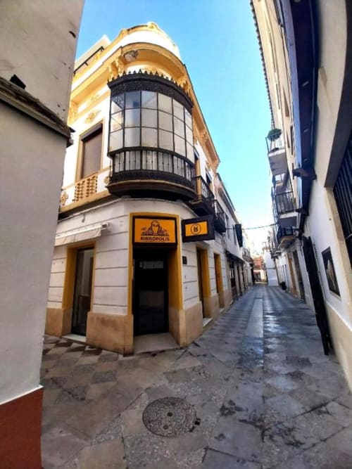 Histórico edificio en esquina con fachada amarilla y blanca en Jerez de la Frontera, con entrada al bar Birrópolis y arcos