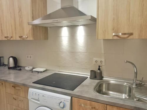 Cocina moderna de apartamento en Jerez de la Frontera con muebles de madera, electrodomésticos de acero inoxidable y fregadero