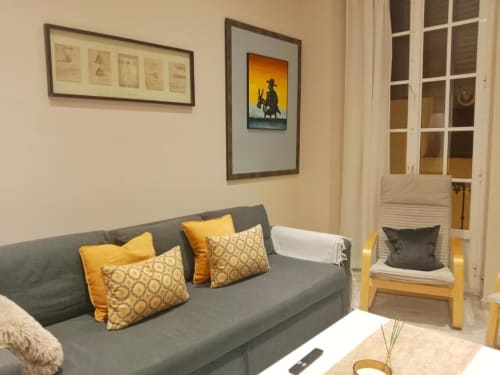 Acogedora sala de estar en Top Home Integra, Jerez de la Frontera, con sofá gris, detalles amarillos y cuadros enmarcados