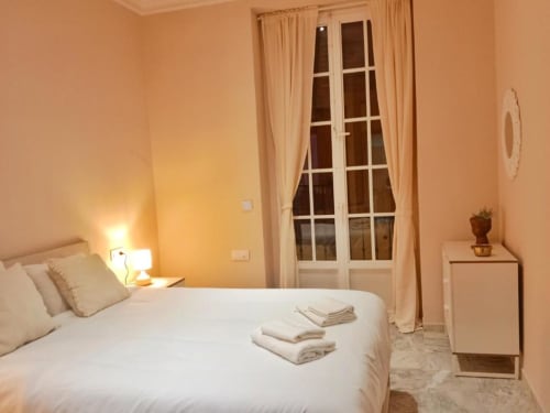 Luminosa habitación en Top Home Integra de Jerez de la Frontera con ropa de cama blanca, lámpara y puertas con vistas a la ciudad