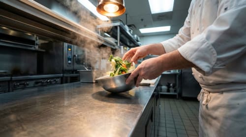 Chef préparant les légumes dans la cuisine moderne de la Résidence hôtelière du Coiroux, Aubazine