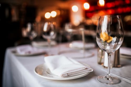 Élégante mise de table dans la salle à manger de la Résidence hôtelière du Coiroux à Aubazine avec verre de vin et couverts