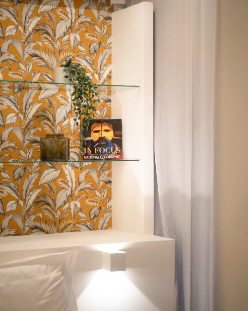 Bagno moderno della IV House Roma B&B con carta da parati botanica dorata, ripiano in vetro sospeso e rivista National Geographic