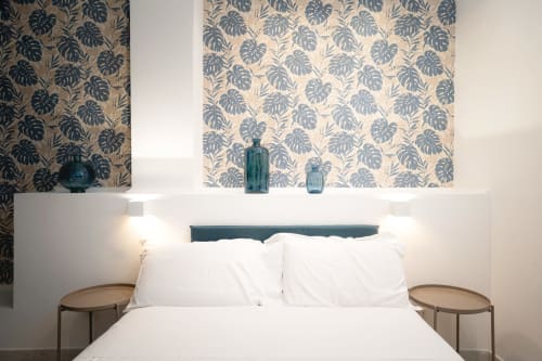 Camera moderna presso IV House Rome B&B con biancheria bianca, carta da parati con foglie di monstera e accenti in vetro teal
