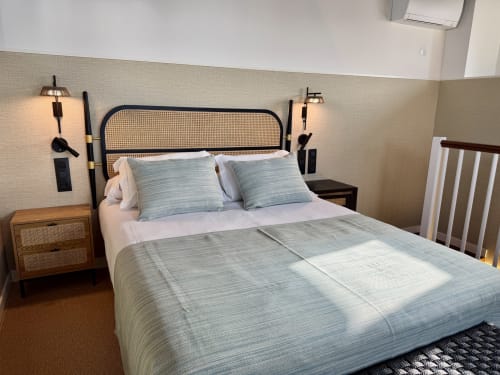 Habitación moderna en Casa Rural San Andrés de Teixido con cabecero de ratán, ropa de cama a rayas azules, mesita de noche de madera y vista al mar