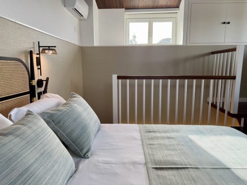 Habitación moderna con cabecera de rattán, ropa de cama a rayas y cuna de madera en Casa Rural San Andrés de Teixido