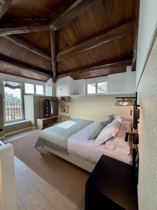 Dormitorio moderno con vigas de madera vista, ventanales con vistas al mar y mobiliario contemporáneo en Casa Rural San Andres de Teixido,