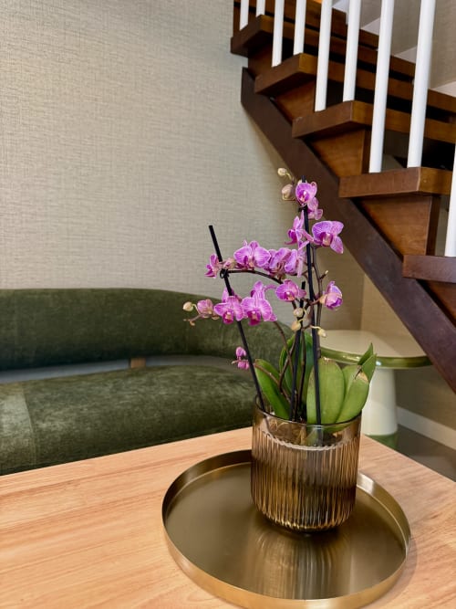 Orquídeas rosas en florero texturado sobre bandeja de latón en el área Negra de la Casa Rural San Andrés de Teixido, Galicia