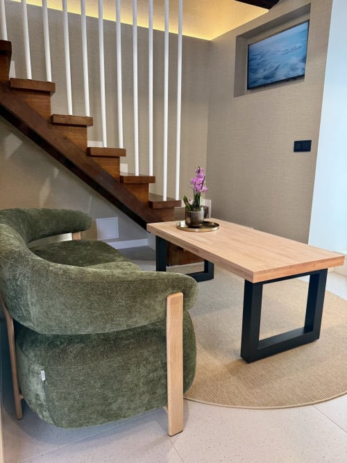 Área de estar moderna con sillón verde, mesa de madera y escalera iluminada en Casa Rural San Andres de Teixido