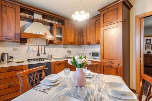 "Living area of ​​Casa Meravigliosa in Fontanafredda with a dining table set for four, matching wooden chairs, and a classic-style kitchen."