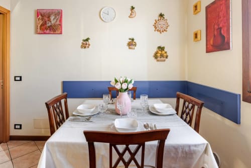 Elegant dining room at Casa Meravigliosa with set table, wood chairs, blue wainscoting, and decorative wall art in Friuli