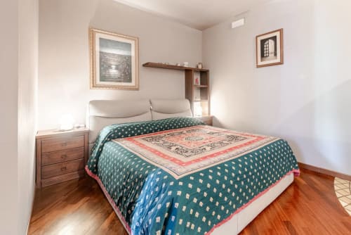 Double bedroom at Casa Meravigliosa in Fontanafredda with a modern bed with an upholstered headboard, dark wood floors, wooden bedside tables, and classic-style decorative paintings.