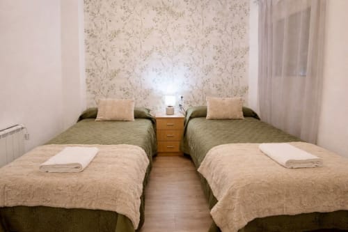 Habitación doble del apartamento Gestyp-AT en Mérida, con colchas verdes, decoración neutral y piso de madera