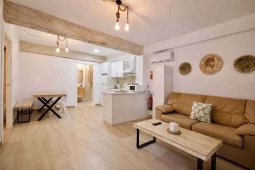 Moderno apartamento en Mérida con sala diáfana, sofá de cuero tostado, vigas de madera y cocina con gabinetes blancos