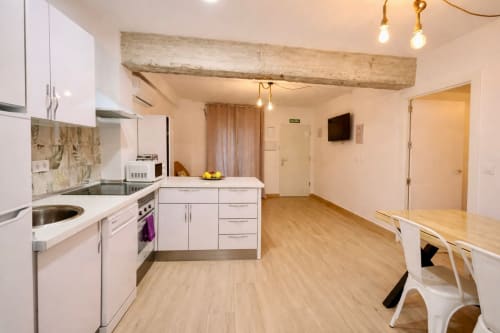 Moderna cocina y sala de estar en Mérida con gabinetes blancos, viga de madera, mesa de comedor y plano abierto