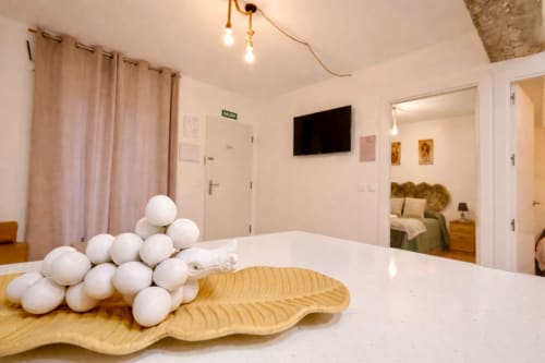 Apartamento moderno en Mérida con esferas decorativas blancas, escultura de hoja en madera, TV montada en pared y vista abierta de la ciudad