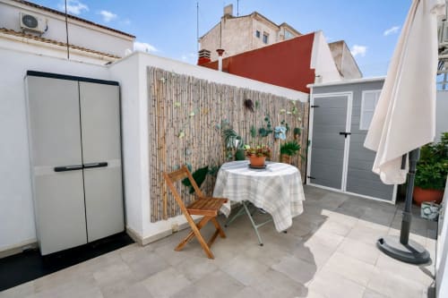 Terraza en azotea del apartamento Gestyp-AT en Mérida con mesa de comedor, silla de madera, plantas en maceta y vistas a la ciudad
