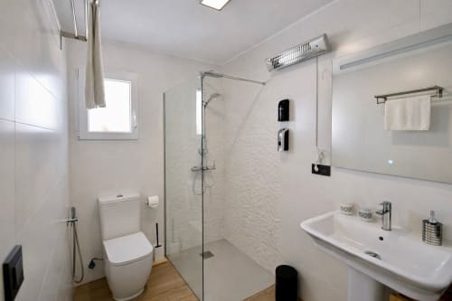 Baño moderno con ducha a ras de suelo, inodoro y lavamanos en apartamento Gestyp-AT, Mérida
