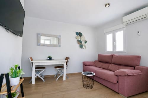Sala moderna de apartamento en Mérida con sofá granate, mesa de comedor blanca y piso de madera