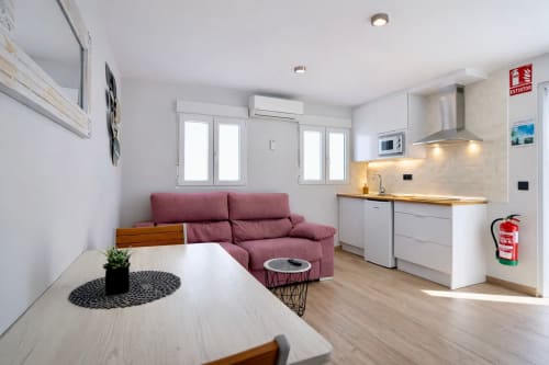 Moderno apartamento en Mérida con sofá burdeos, cocina y vistas a la ciudad