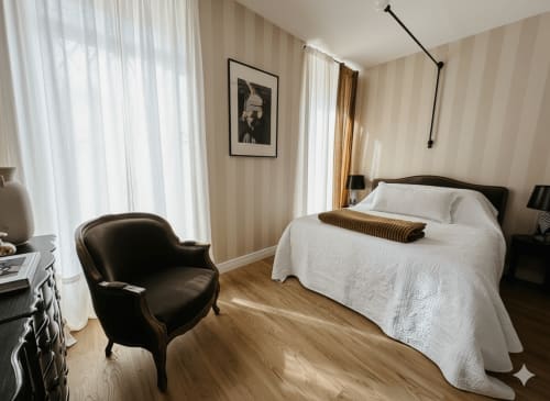 Chambre élégante à Alombre à Lectoure avec lit queen-size, fauteuil noir, parquet et vue sur les montagnes
