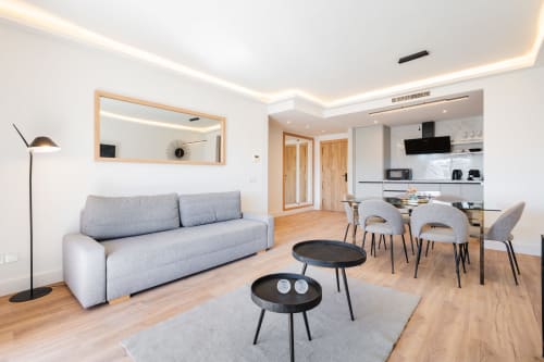 Modern Marbella apartment with gray sofa, dining area, equipped kitchen, and wooden floors in Puerto Banús