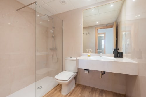 Modern bathroom in Marina Banús apartment with walk-in shower, white vanity, and wooden floor at Marbella Home Rentals