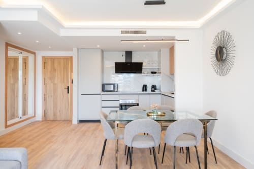 Modern Marbella apartment dining area with kitchen, wooden doors, gray chairs, and contemporary decor in Puerto Banús