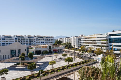 Modern Marbella apartment complex with city view, Marina Banús area featuring contemporary architecture and landscaped plaza