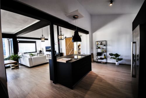 Modern hotel suite at Escanda Building Solutions with black beam ceiling, kitchen island, wooden floors, and contemporary