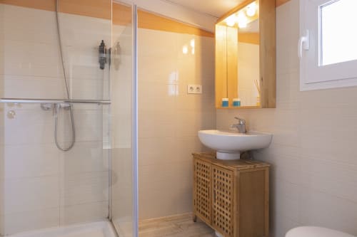 Baño moderno en el penthouse Ab Be, Málaga, con ducha abierta, lavabo tipo vasija, tocador de madera y calefacción