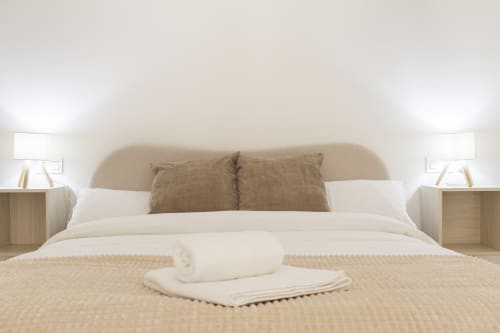 Lujoso dormitorio en el Ático Ab Be, Málaga con tonos neutros, cabecero beis, ropa blanca y toallas enrolladas en la cama